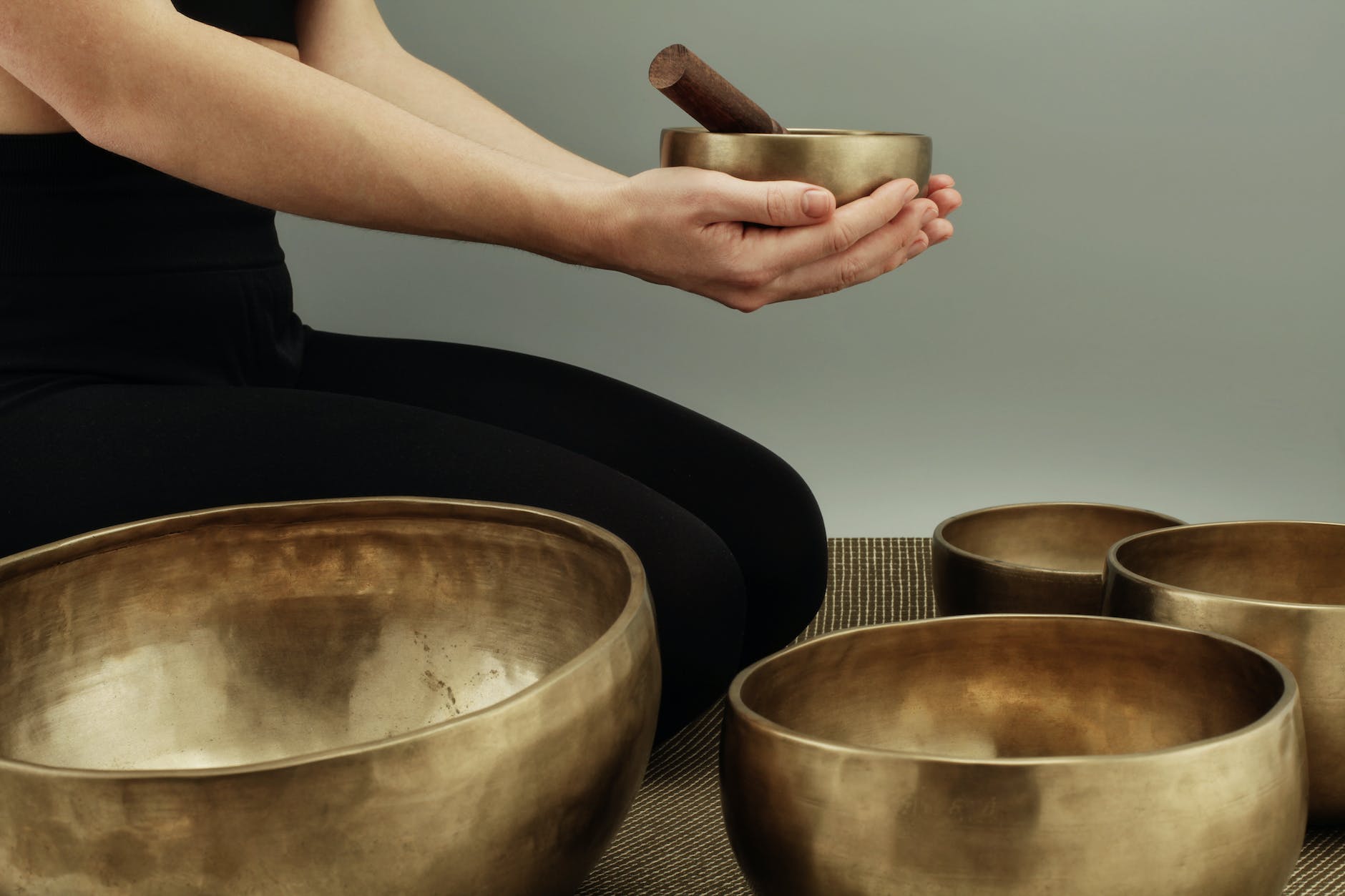 woman sitting on rug near brass bowls